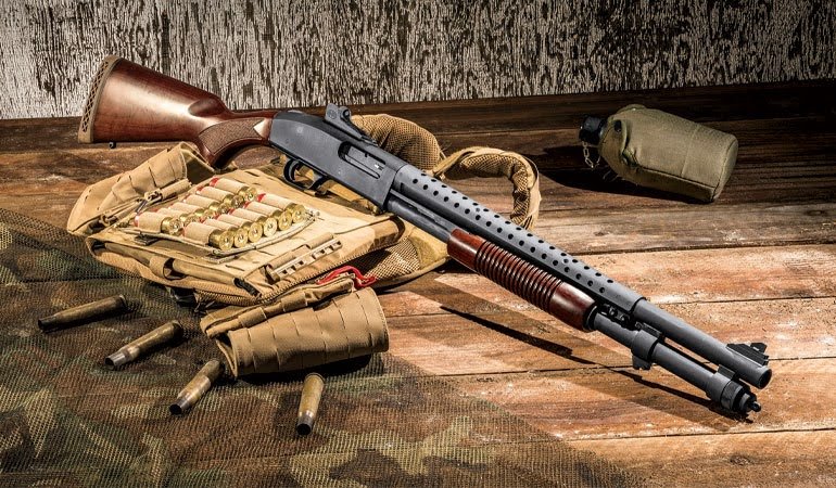 Mossberg 590A1 Retrograde pump shotgun with vintage wood furniture and modern heat shield surrounded by shotgun shells and tactical gear