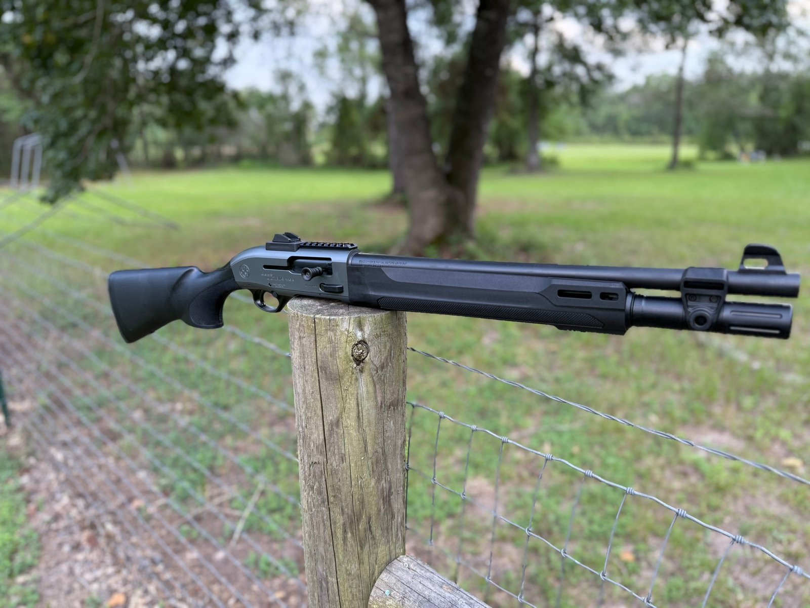 Beretta A300 Ultima Patrol semi-auto shotgun positioned on a fence post in a rural outdoor setting
