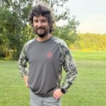 Man wearing Bassdash shirt in field.