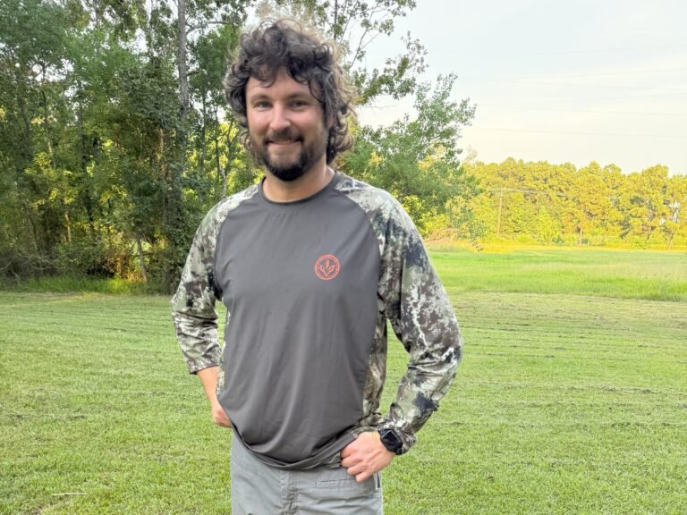Man wearing Bassdash shirt in field.
