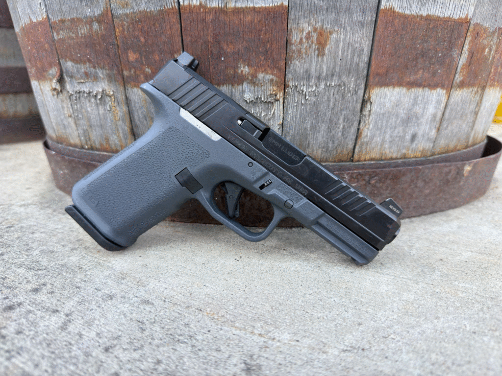 Ruger RXM Glock 19 clone compact 9mm pistol with Magpul EHG grip resting against a wooden barrel background.