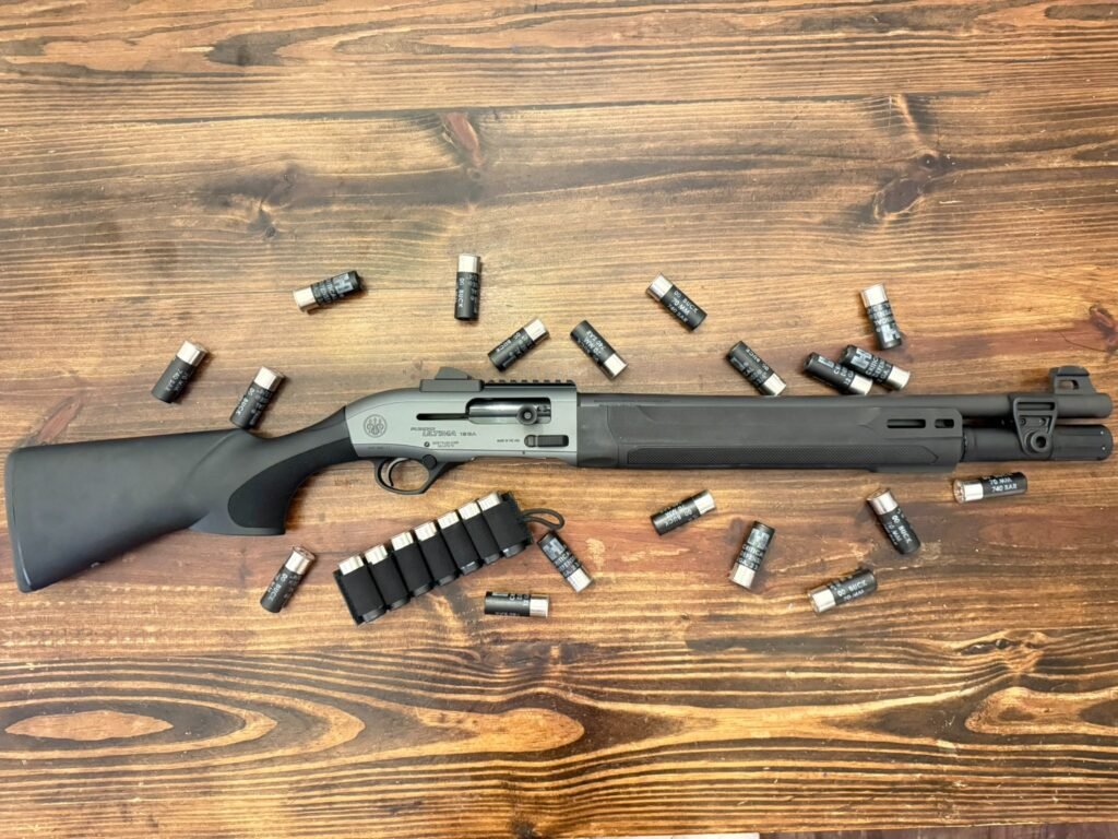 Beretta A300 Ultima Patrol semi-automatic shotgun laid flat on a wooden surface, surrounded by 12-gauge 00 buckshot shells and a side-saddle shell carrier, illustrating a shotgun ammo for home defense setup.