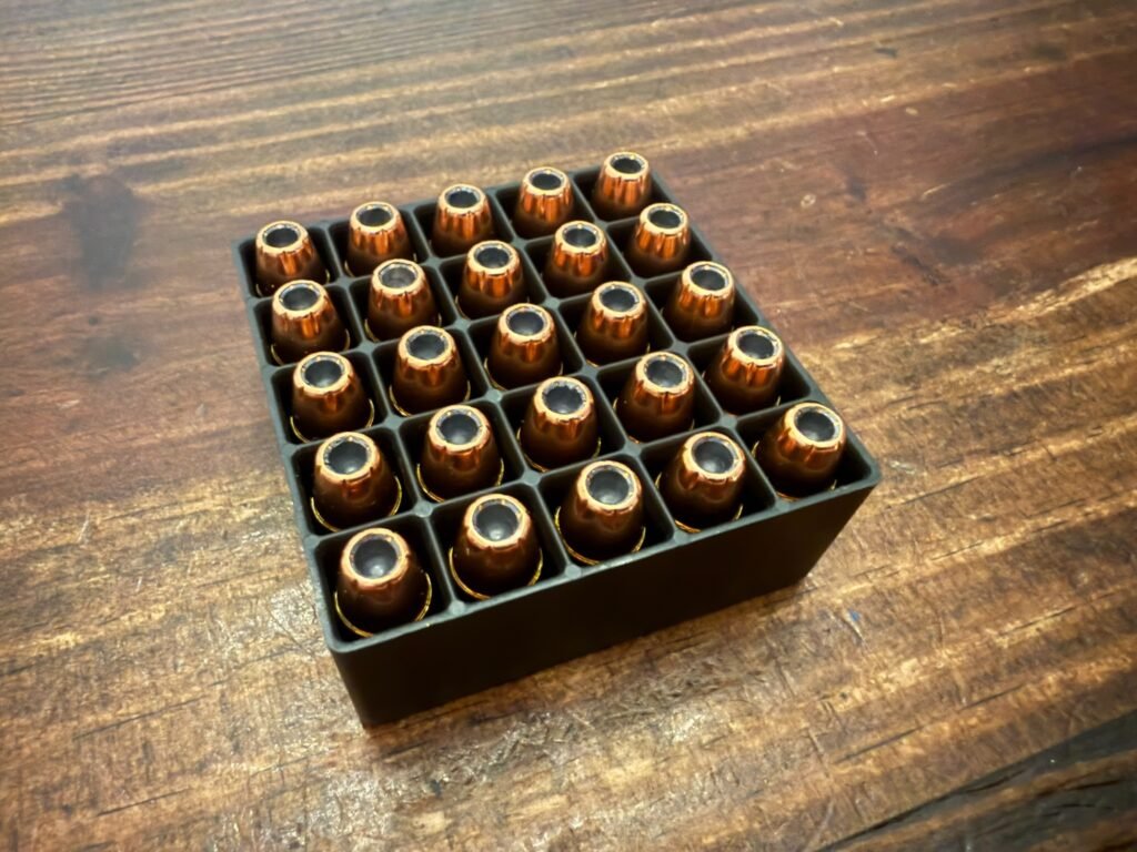 Tray of jacketed hollow point handgun cartridges viewed from above, showing bullet cavities and consistent loading, illustrating modern home defense ammunition used for controlled expansion and reliability.