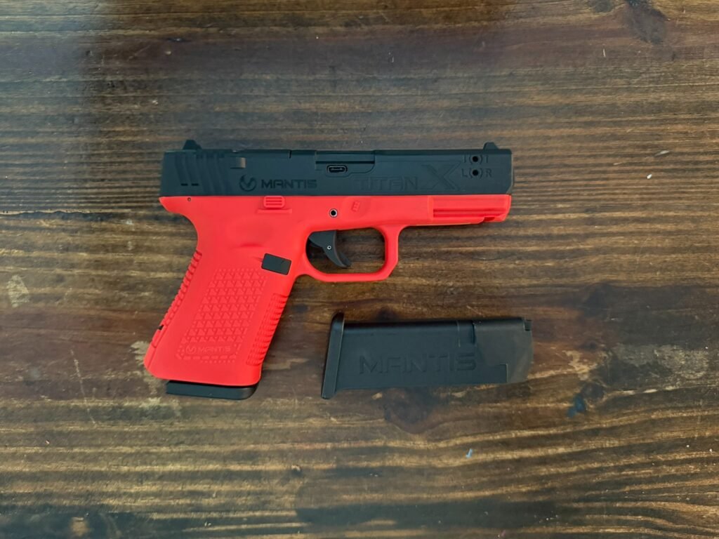 Mantis TitanX laser training pistol with magazine removed shown on table for dry fire training overview