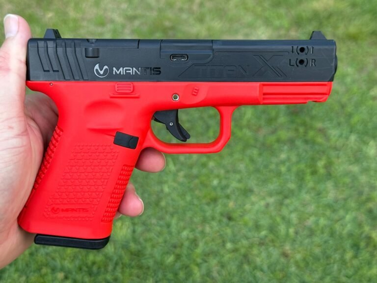 Mantis TitanX laser training pistol held in hand, showing red frame and black slide during dry fire training setup