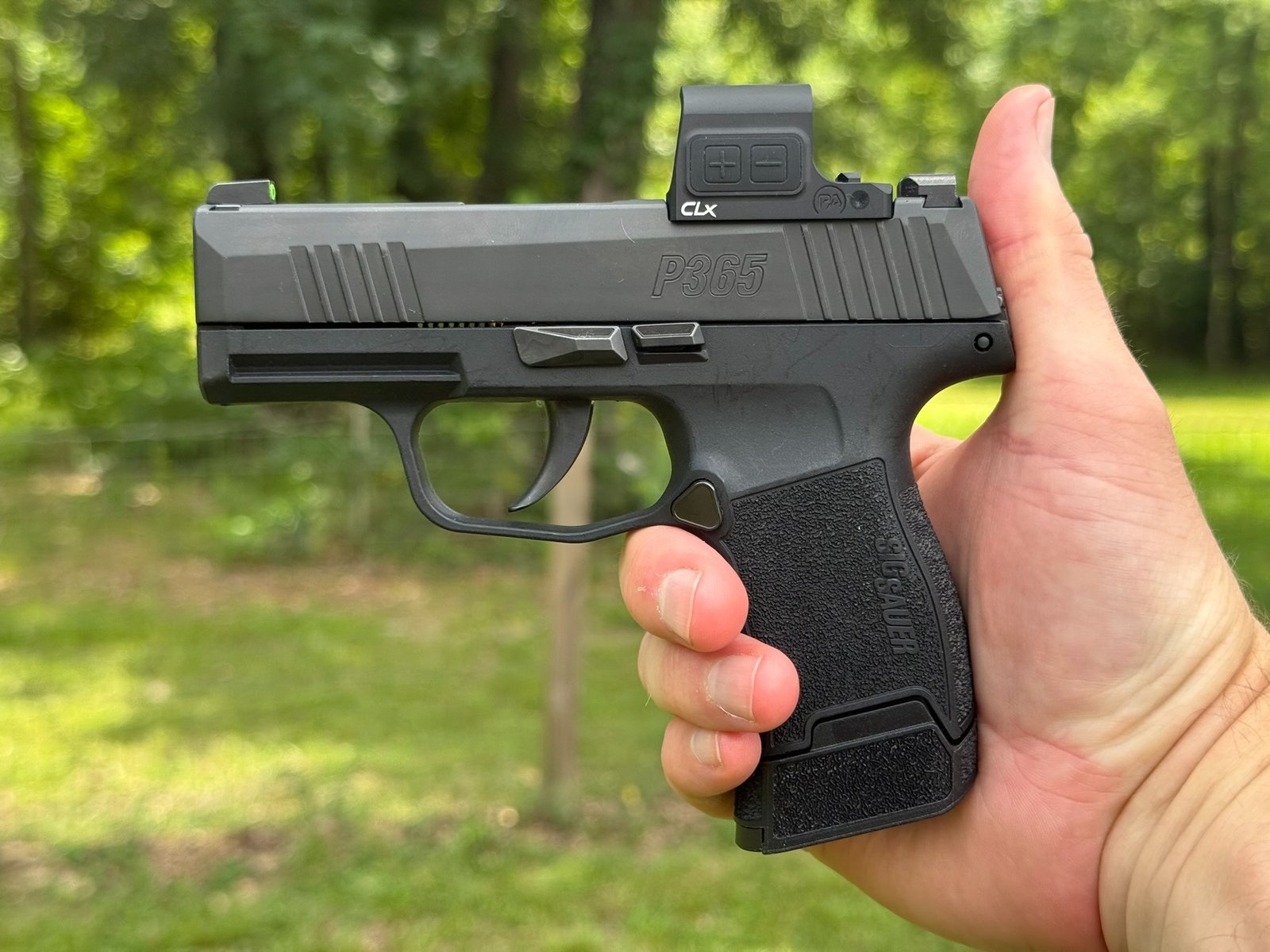 SIG P365 pistol with a Primary Arms CLx Enclosed Reflex Sight mounted, shown in profile while being held outdoors during testing.