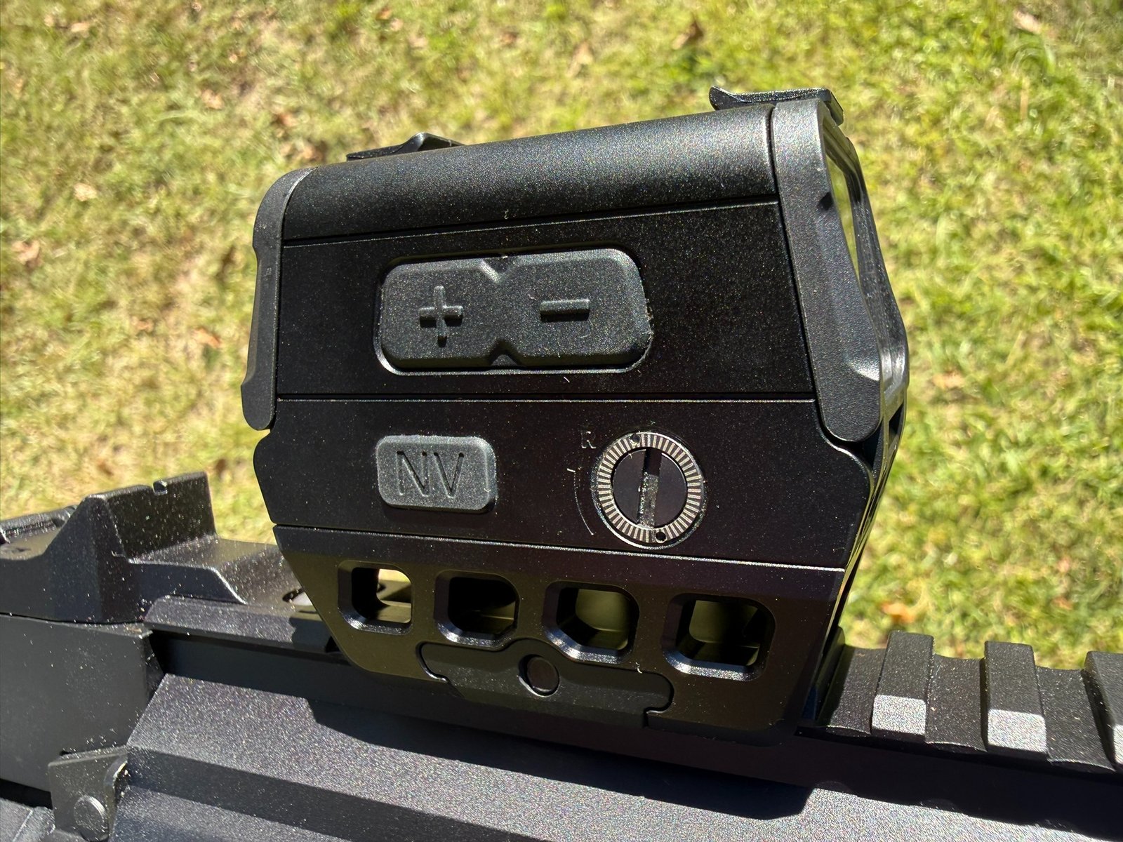 Close-up of the Osight R red dot showing its brightness buttons, NV button, and windage adjustment dial