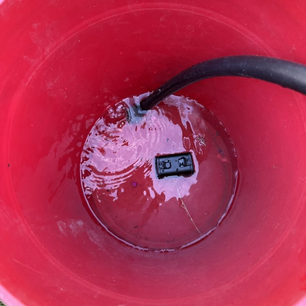 Osight R red dot sight submerged in a five-gallon bucket during waterproof testing for the Osight R Review.